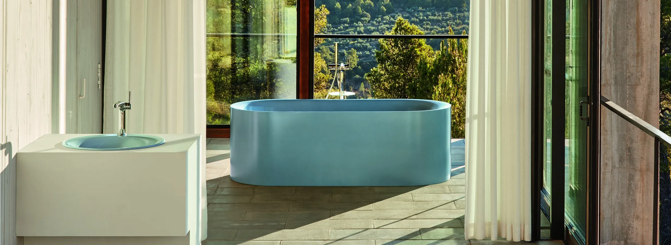 Badewanne BetteLux in Blau-Satin mit Blick durch Baumwipfel