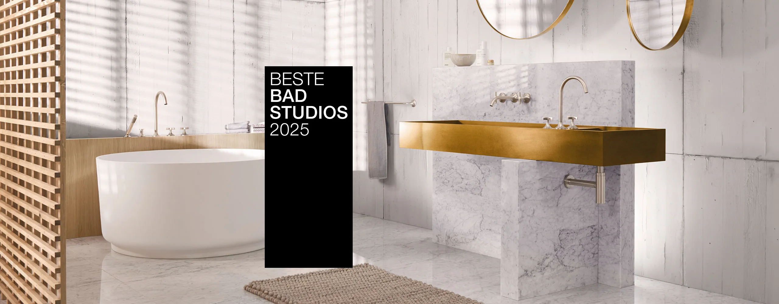 Ein stilvolles Bad mit goldenen Armaturen, Marmorwaschtisch und freistehender Badewanne. Ein schwarzer Banner mit "Beste Badstudios 2025" ist prominent im Bild.