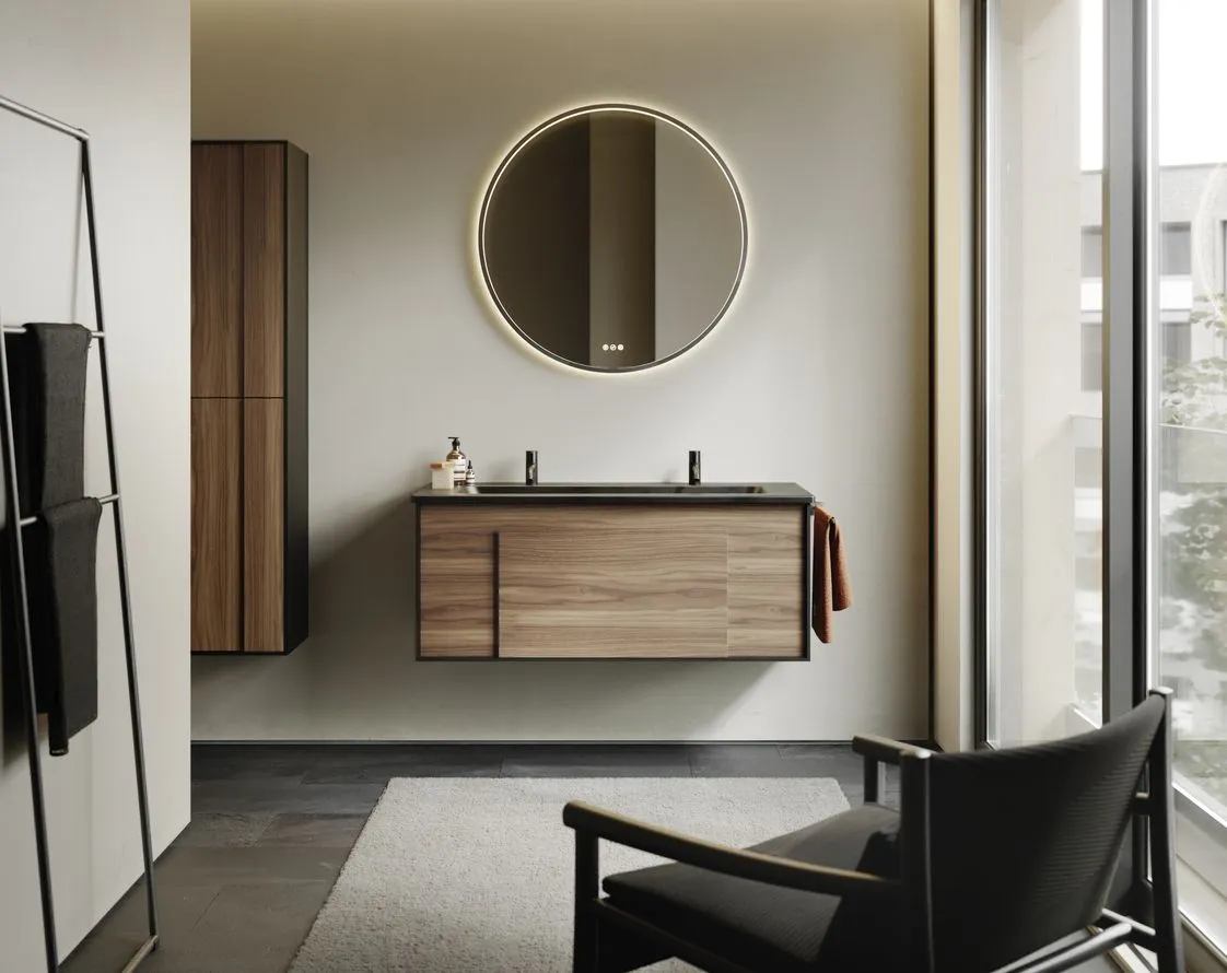 Ein stilvolles Badezimmer zeigt ein Möbelset aus der Serie burgbad Modo mit einem schwebenden Waschtisch in Holzoptik und schwarzer Waschtischplatte