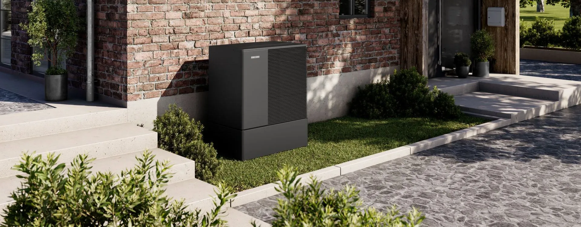 Eine schwarze Waermepumpe der WPL-A-Serie von Stiebel Eltron steht auf einer Rasenflaeche vor einem Altbau.