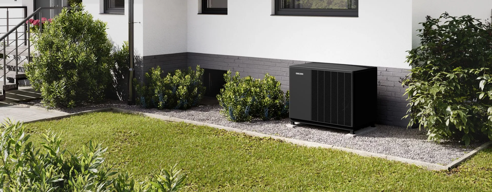 Eine Wärmepumpe von Stiebel Eltron steht im Garten auf einem schmalen Kiesbettstreifen vor dem Einfamilienhaus.