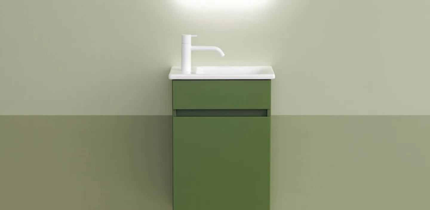 Ein in ocker-grün gehaltenes Gästebad mt schmalem, grünem Waschtisch der Kollektion Lin20 von burgbad auf dem eine seitlich angebrachte, weiße Armatur montiert ist.
