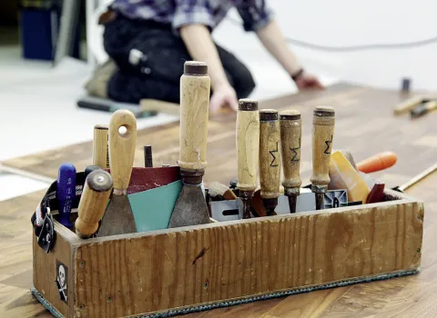 Werkzeugkasten eines Parkettlegers auf dem noch nicht fertiggestellten Parkett.