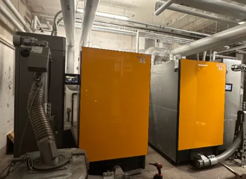 Heizungsraum mit großen Heizkesseln in gelben Gehäusen, angeschlossenen Rohrleitungen und technischer Infrastruktur.