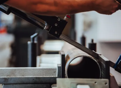 Nahaufnahme eines Metallrohrs, das in einer Werkstatt mit einer Maschine präzise zugesägt wird.