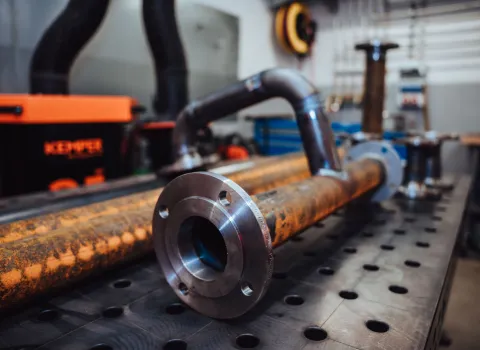 Metallrohr mit Flanschverbindungen auf einer Werkbank in der Werkstatt – vorbereitet für die weitere Verarbeitung und Montage.
