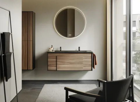 Ein stilvolles Badezimmer zeigt ein Möbelset aus der Serie burgbad Modo mit einem schwebenden Waschtisch in Holzoptik und schwarzer Waschtischplatte