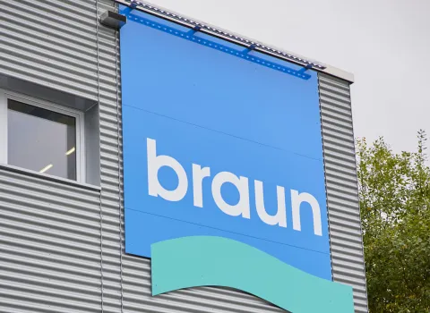 Großes blaues Gottfried-Braun-GmbH-Firmenlogo an der metallverkleideten Außenfassade eines modernen Gebäudes.
