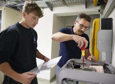 Zwei Mitarbeitende der Gottfried Braun GmbH arbeiten gemeinsam an einem elektrischen Gerät.