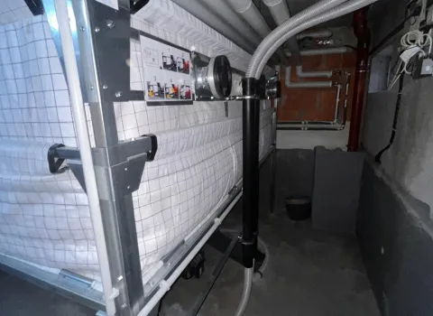 Das Bild zeigt einen Lagerraum mit einem großen, in einem Metallrahmen gespannten Gewebesilo zur Lagerung von Holzpellets.