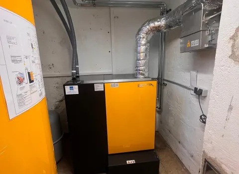 Das Bild zeigt eine moderne Pelletheizung der Marke ETA in einem kleinen Technikraum mit weiß verputzten Wänden.