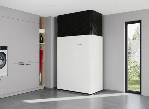 Das All-in-one Waermepumpensystem LWZ von Stiebel Eltron in einem Technikraum neben einem schmalen Fenster.