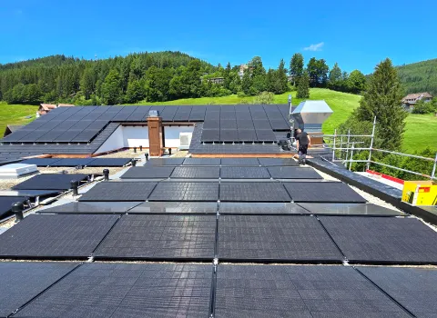 Große Photovoltaikanlage auf Flachdach eines Gebäudes mit Blick auf Landschaft und Wälder.