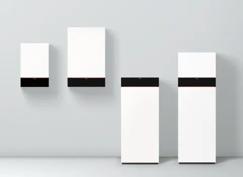 Vier Gasbrennwertgeäte der Vitodens-Serie von Viessmann aufgereiht vor einer grauen Wand.