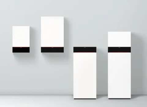 Vier Gasbrennwertgeäte der Vitodens-Serie von Viessmann aufgereiht vor einer grauen Wand.