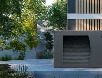 Eine Solvis-Wärmepumpe mit Lamellenfront steht auf einer Terrasse neben einem modernen Holzfassadenhaus, umgeben von Bäumen und Natur.