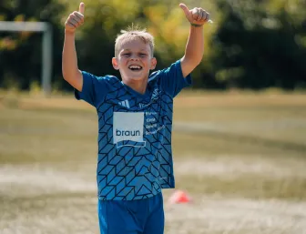 Ein Kind jubelt auf dem Fussballplatz.