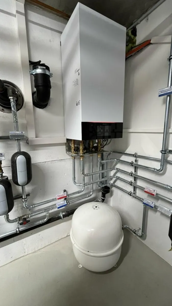 Das Bild zeigt eine Viessmann-Wärmepumpe mit wandmontierter Inneneinheit, die an ein komplexes Netz aus Edelstahlrohren angeschlossen ist.