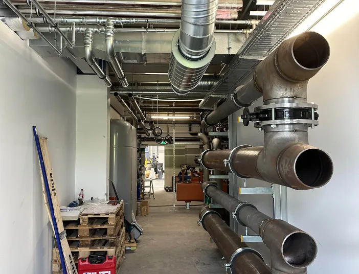 Maschinenraum mit groß dimensionierten Rohrleitungen, Lüftungskanälen und technischen Installationen für eine industrielle Kälteanlage.