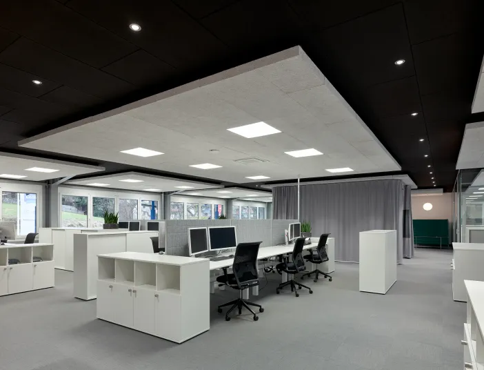 Modernes, helles Großraumbüro der Gottfried Braun GmbH mit weißen Arbeitsplätzen, Monitoren und großen Fensterfronten.